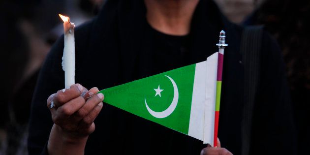 A woman holds a candle and a Pakistani flag as she takes part in a protest against terrorism in Islamabad March 17, 2015. Suicide bombings outside two churches in Lahore killed 14 people and wounded nearly 80 others during services on Sunday in attacks claimed by a faction of the Pakistani Taliban. REUTERS/Faisal Mahmood