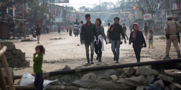 Indian pedestrians walk past temporary roadblocks on the outskirts of Imphal on December 20, 2016, during an ongoing economic blockade led by Naga militant groups in the north-eastern Indian state of Manipur.