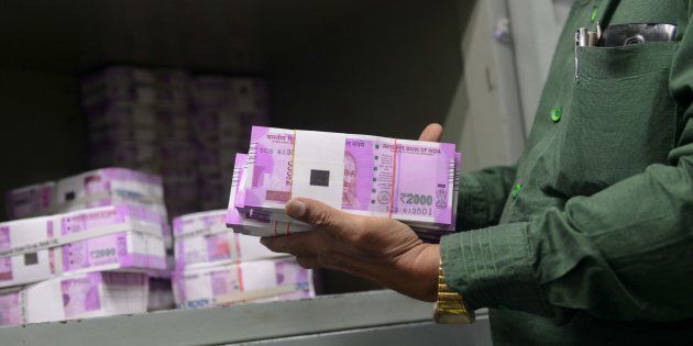 An Indian bank employee checks stacks of new 2000 rupee notes in Ahmedabad on November 11, 2016.
