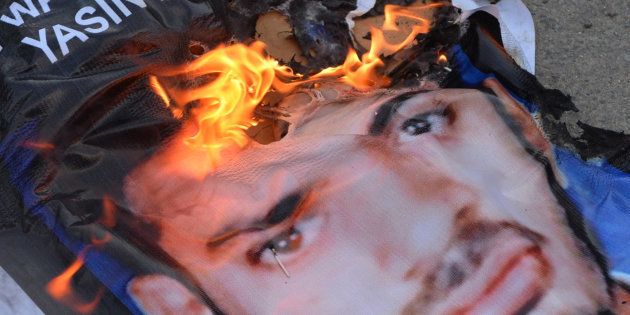 A poster of Yasin Bhatkal, an alleged founder of the Indian Mujahideen, burns after being set on fire by demonstrators celebrating his arrest in Bangalore on August 29, 2013.