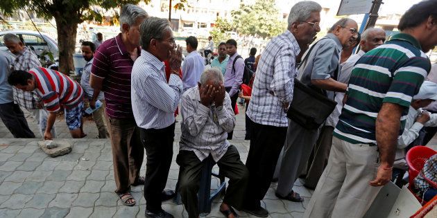 A man sits in a queue to deposit or exchange his old high denomination banknotes outside a bank in Ahmedabad, India November 21, 2016. REUTERS/Amit Dave