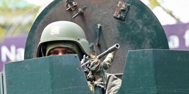 An Indian Border Security Force (BSF) soldier stands guard on top of an armoured vehicle outside a polling station in Srinagar on April 8, 2017.