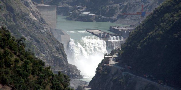 Water flows on the banks of Chenab River with the Baglihar hydroelectric project in the background.