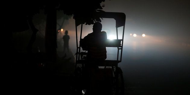 A rickshaw puller waits for customers along a roadside amidst heavy smog in New Delhi, India November 6, 2016.