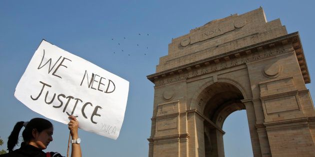 A demonstrator holds a placard in front of the India Gate.