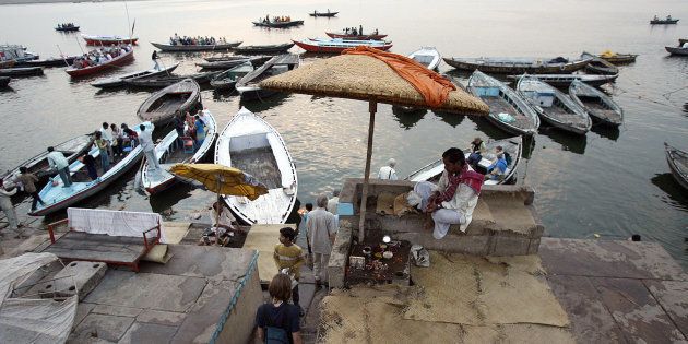 FILE PHOTO: Tourists board a boat, as a Hindu priest looks on, at the Dashashumedh ghat on the banks of the Ganga river in Varanasi, 09 March 2006.