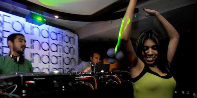A woman dances as Indian disc-jockeys Nasha (C) and Nucleya (L) play music at a nightclub in New Delhi.