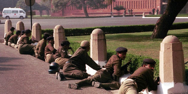 Delhi police commandos take cover outside the Indian parliament buildings December 13, 2001 in New Delhi, India.