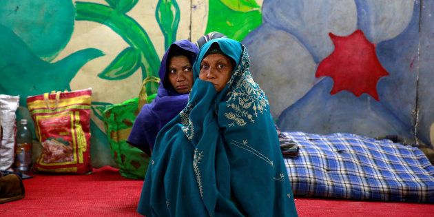 Women wrap themselves in blankets in a government shelter for homeless people to escape the cold in Delhi, India January 16, 2017.