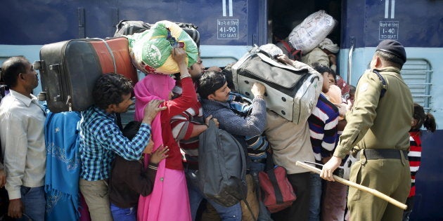 A policeman keeps order as people board a passenger train at a railway station in New Delhi.