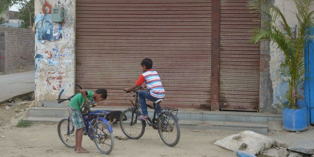 This picture shows children cycling in front of a closed liquor shop near a national highway on the outskirts in Amritsar.