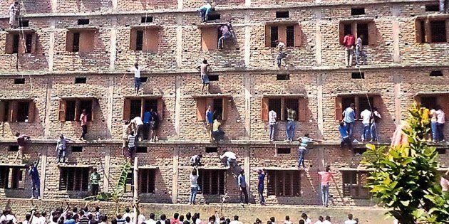 In this photograph taken on March 19, 2015, Indian relatives of students taking school exams climb the walls of the exam building to help pass candidates answers to questions in Vaishali in Bihar.