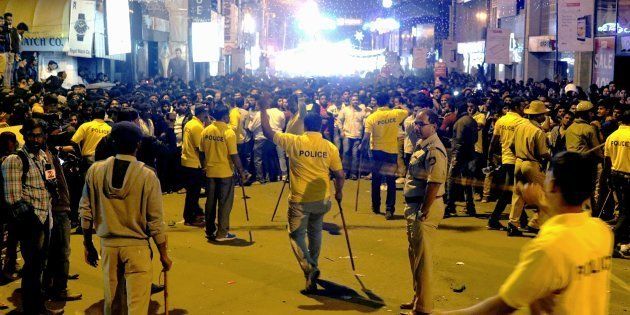Indian police personnel holding 'lathi' sticks try to manage crowds during New Year's Eve celebrations in Bangalore on January 1, 2017.
