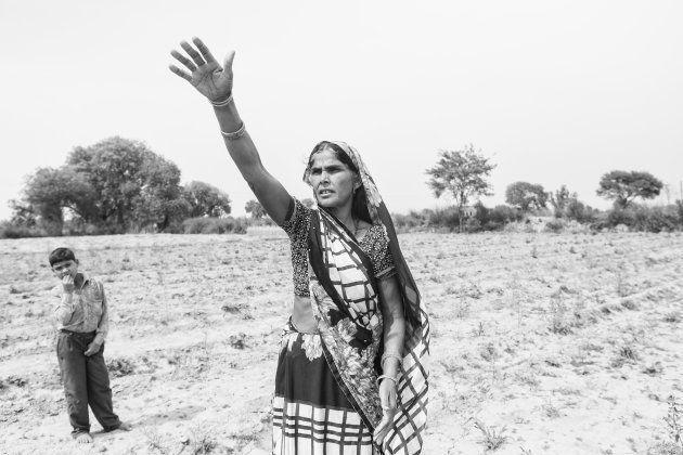 Madhubala, Sheetal's mother, gestures as she stands in the middle of the family land. All the crops have died after the Thakurs cut off their water supply.