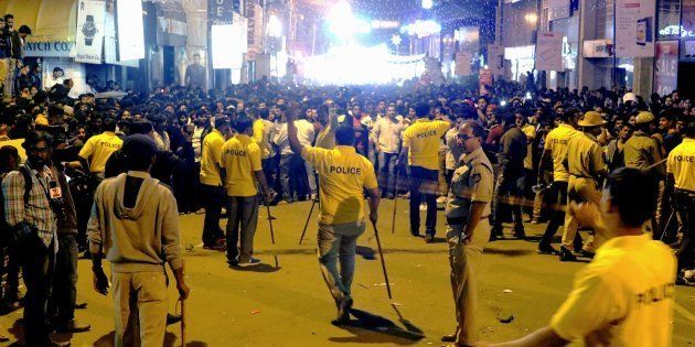 In this photograph taken on January 1, 2017, Indian police personnel holding 'lathi' sticks try to manage crowds during New Year's Eve celebrations in Bangalore on January 1, 2017.An Indian minister faced a severe backlash January 3 after he criticised women for dressing 'like westerners' at a New Year's eve celebration where a mob allegedly carried out a series of sex assaults. Although police have yet to charge anyone in connection with the violence on New Year's Eve in Bangalore, local media have carried testimony and photos of victims cowering from their attackers or fleeing for safety. / AFP / STR (Photo credit should read STR/AFP/Getty Images)