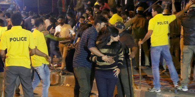In this photograph taken on January 1, 2017, an Indian man helps a woman (C) leave as police personnel try to manage crowds during New Year's Eve celebrations in Bangalore on January 1, 2017.