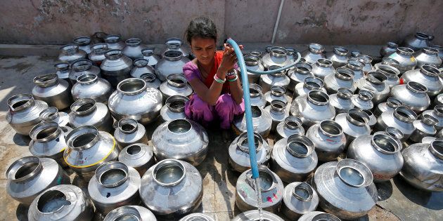 A girl fills metal pitchers with drinking water from a tubewell outside a temple in Ahmedabad, India March 30, 2017. REUTERS/Amit Dave