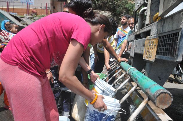 Indian residents gather to collect drinking water with buckets from a water tanker following water shortages in Shimla, in the northern state of Himachal Pradesh on June 2, 2018. - Helicopters doused forest fires raging near the drought-stricken Indian resort of Shimla on May 1 ore police were deployed to guard water tankers in the historic Himalayan town. Shimla's water shortage has been worsening for years but reached crisis point when supplies ran out last month, just as the population of 175,000 started growing by up to 100,000 for the summer season. (Photo by - / AFP) (Photo credit should read -/AFP/Getty Images)