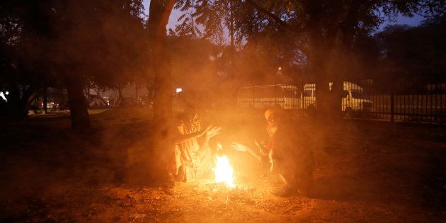 A couple lights a fire to warm themselves on a cold winter evening in New Delhi, India, December 28, 2016. REUTERS/Adnan Abidi