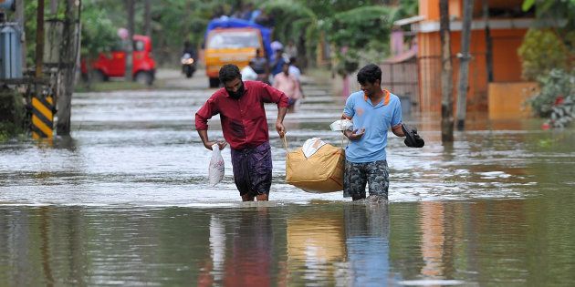People carry food and water aid distributed to those stranded by floods in Pandanad in Alappuzha District in Kerala on August 21, 2018.