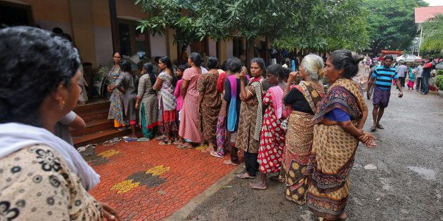Flood-affected women wait to receive relief material at a camp in Chengannur in Kerala on 20 August.