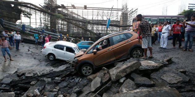 People stand next to the wreckage of vehicles at the site of a bridge that collapsed in Kolkata, India September 4, 2018. REUTERS/Rupak De Chowdhuri