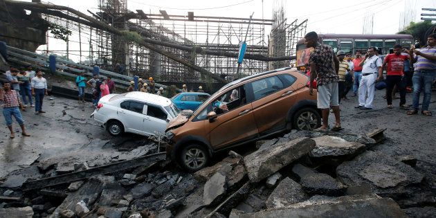 People stand next to the wreckage of vehicles at the site of a bridge that collapsed in Kolkata, India September 4, 2018. REUTERS/Rupak De Chowdhuri TPX IMAGES OF THE DAY