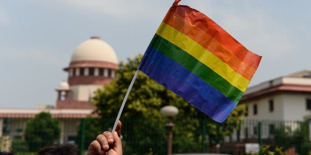 A member of the LGBT community waves a flag outside the Supreme Court building as crowds gathered to celebrate the decision to strike down the colonial-era ban on gay sex.