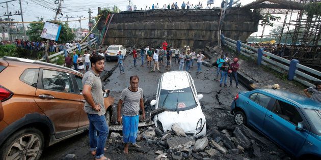 People stand next to the wreckage of vehicles near the Majerhat bridge, which collapsed on Tuesday.