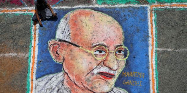 A student sits next to a painting of Mahatma Gandhi as part of Independence Day celebrations.