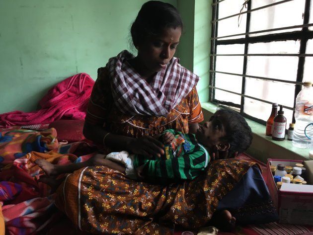 Minnie Suresh, who has breathing difficulties, nurses her two-year-old child. Health department workers at this relief camp in Idukki say she needs to get treatment in a bigger city. With no home or assets left, Minnie doesn't know how she can do that.