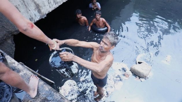 Sanitation workers clean a creek, filled with industrial waste in Sultanpuri, Delhi.