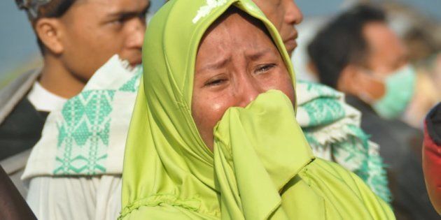 A woman cries as people look at the damages after an earthquake and a tsunami hit Palu, on Sulawesi island on September 29, 2018.