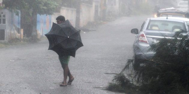 A man tries to hold his umbrella during strong winds and rain caused by Cyclone Titli, near Gopalpur on the Bay of Bengal coast, Ganjam district in Odisha.
