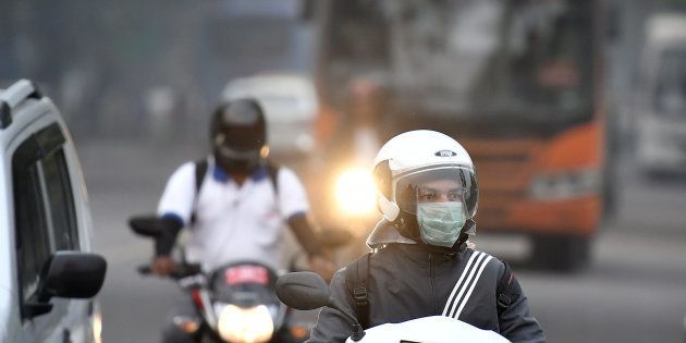A motorcyclist wearing a face mask drives along a road in New Delhi.