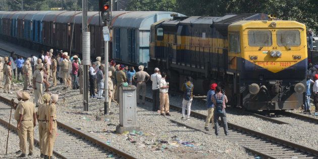 Police stand guard as a freight train passes along rail tracks towards Amritsar railway station, two days after the train accident.