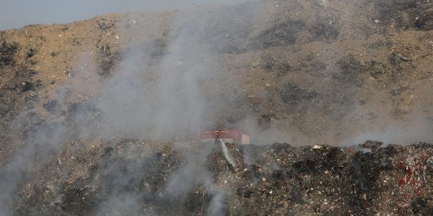 A firefighter tries to douse fire as smoke billows from the burning garbage at the Bhalswa landfill site in Delhi, India, October 22, 2018. REUTERS/Altaf Hussain