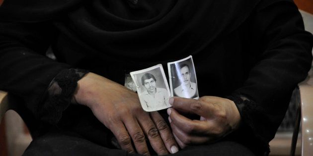 A woman shows picture of her relatives who were killed in the Hashimpura massacre in 1987.