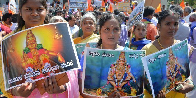 Devotees of Ayyappa hold posters of the deity at a rally in Bangalore on October 27, 2018.
