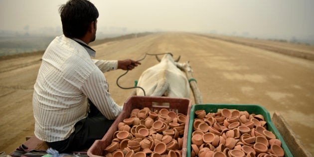 A man selling traditional earthen lamps ahead of Diwali festival, rides a bullock cart through an under construction road on a foggy day in Greater Noida, near New Delhi, India, Monday, Nov.5, 2018. With air quality reduced to