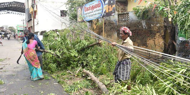 Residents clear away fallen trees near the train station in Nagapattinam in India's southern Tamil Nadu state on November 16, 2018, after a cyclone struck the region.
