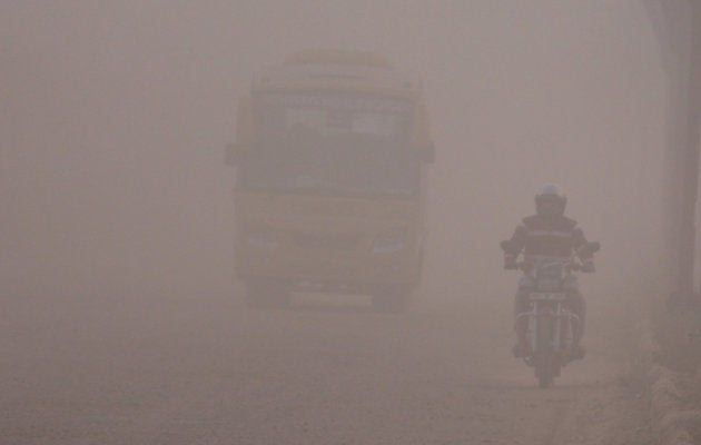 Commuters on a dusty road in Gurugram.