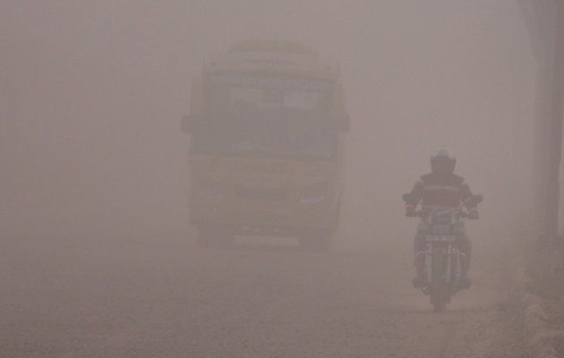 Commuters on a dusty road in Gurugram.