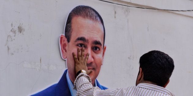 An Indian supporters of the Congress Party keeps his hand on the face of a cut out of billionaire jeweller Nirav Modi during a protest in New Delhi on February 16, 2018.