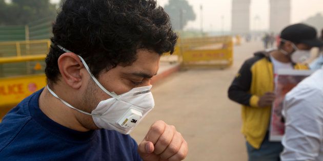 A man coughs even after wearing a mask a day after Diwali festival in New Delhi