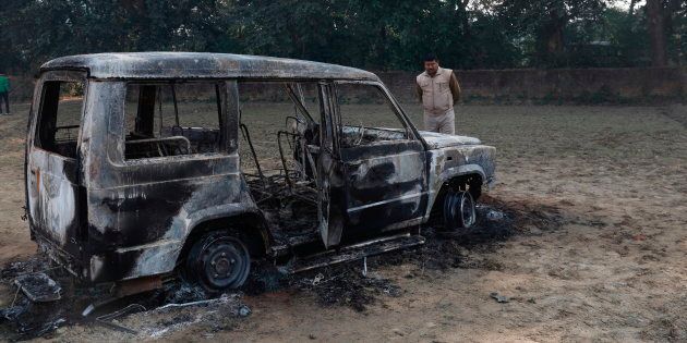 A police officer inspects the vandalised remains of a car in which Inspector Subodh Kumar Singh was attacked.