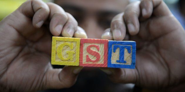 An Indian consumer goods trader shows letters GST representing 'Goods and Services Tax' (GST) at his shop in Hyderabad on August 3, 2016.