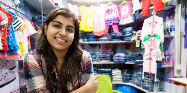 Young Indian woman selling clothes at a small store in a shopping mall in Delhi, India.