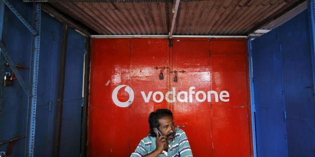 A retail shop owner speaks on his mobile phone outside his closed shop shutters painted with an advertisement for Vodafone at a market in the southern Indian city of Chennai December 30, 2013. REUTERS/Babu/File photo TPX IMAGES OF THE DAY
