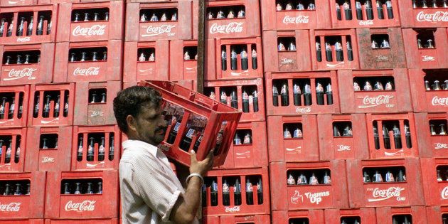 A worker carries a crate of Coca Cola at the local dealer in Jammu.